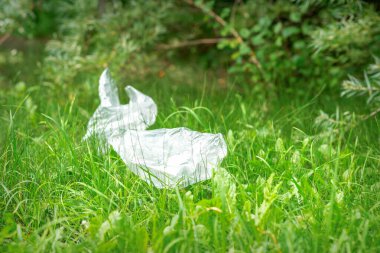 Parktaki yeşil çimlerin üzerinde duran boş plastik poşetler kullanılmış.