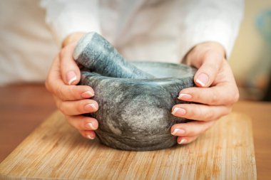 Havan ve tokmak kesme tahtasındaki kadın ellerde