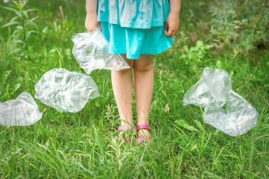 Parktaki döküntüleri temizlerken küçük bir kızın ellerinde boş plastik torba kullanılmış.