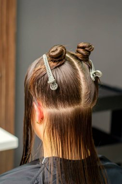 Kadın saçlarını berber dükkanında klipslerle bölümlere ayırdı.