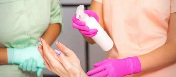 Esteticista Luvas Proteção Borracha Desinfecta Mãos Uma Mulher Com Spray — Fotografia de Stock