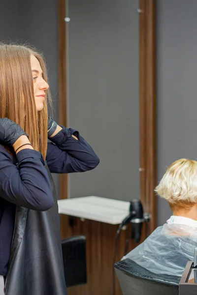 Kobieta Fryzjer Zakłada Czarny Fartuch Przed Obcięciem Włosów Klienta — Zdjęcie stockowe