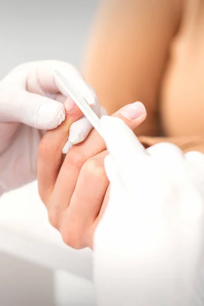 Pinças de prego na mão do mestre manicure feminino colocando a