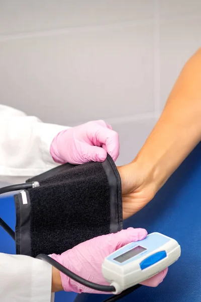 Stock image Nurse or female doctor puts on tonometer on arm of young woman in the hospital