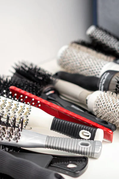 Set of different hair brushes and combs lying on the white table