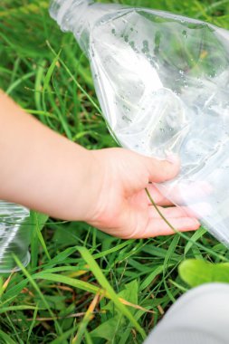 Parktaki döküntüleri temizlerken küçük bir kızın ellerinde boş plastik torba kullanılmış.