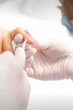 Manikür ustası manikürcüde tırnaklarını tırnak makasıyla kesiyor.