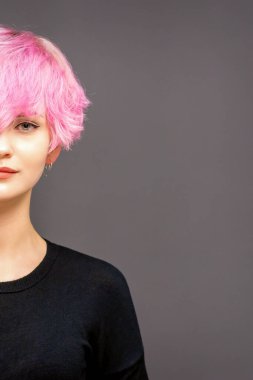 Moda modelinin yarı portresi. Siyah elbiseli, şık, pembe saçlı, siyah arka planda genç bir kadın.