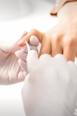 Manikür ustası manikürcüde tırnaklarını tırnak makasıyla kesiyor.