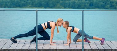 Kadın ve çocuk göl kenarında spor egzersizleri yapıyorlar.