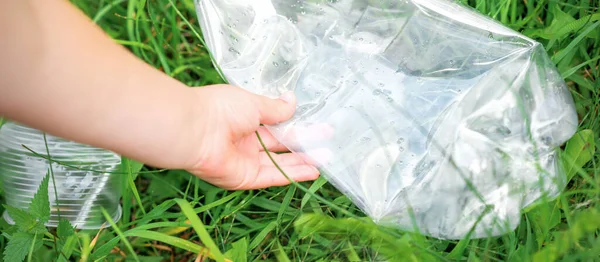 ゴミから公園を掃除しながら少女の手に空のビニール袋を使用 — ストック写真