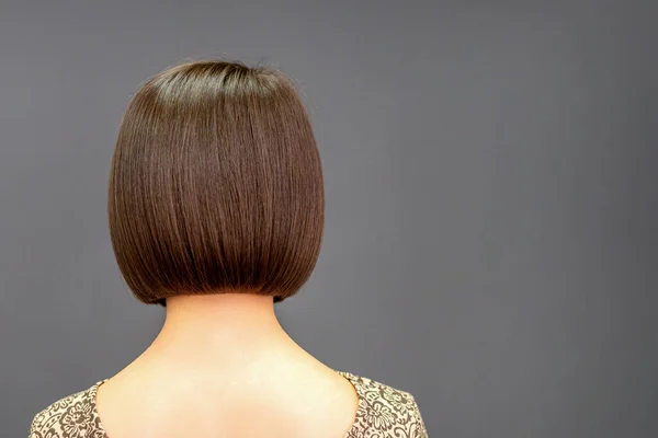 Back view of bob hair of a young woman on dark background