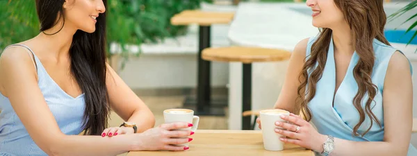 两个年轻美丽的高加索女人坐在露天咖啡馆的桌子边喝咖啡 — 图库照片