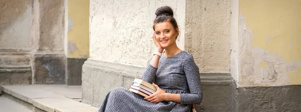 Studentin Langem Kleid Hält Bücher Die Kamera Und Sitzt Auf — Stockfoto