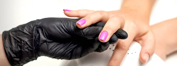 Manicure Master Hand Houdt Een Vrouwelijke Vinger Met Paarse Nagellak — Stockfoto