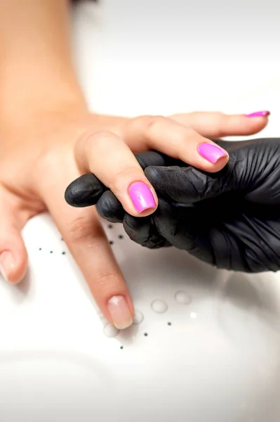 Manicure Master Hand Houdt Een Vrouwelijke Vinger Met Paarse Nagellak — Stockfoto