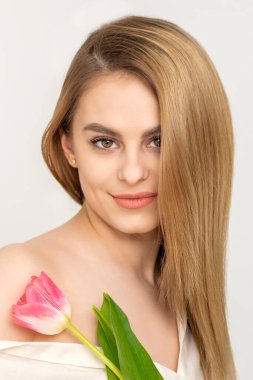 Beyaz arka planda bir lalesi olan güzel beyaz bir kadın.