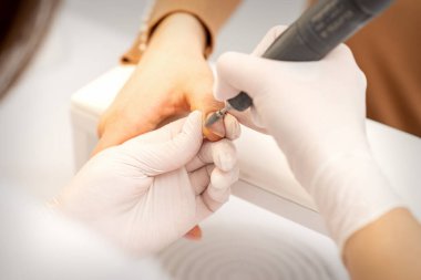 Manikür ustası bir manikürcüde eski tırnak cilasını sökmek için elektrikli oje kullanıyor.