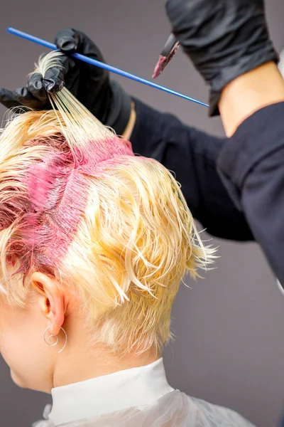 Close Mãos Cabeleireiro Aplicando Tinta Rosa Cabelo Loiro Mulher Salão — Fotografia de Stock