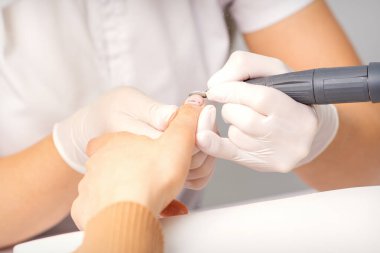 Manikür ustası bir manikürcüde eski tırnak cilasını sökmek için elektrikli oje kullanıyor.