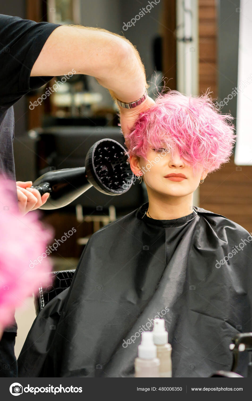 Cabeleireiro seca e modela o cabelo com um secador de cabelo no salão de  beleza