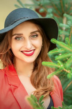 Noel ağacıyla gülümseyen ve kameraya bakan güzel beyaz bir kadının portresi.