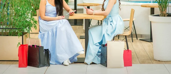 Dos Mujeres Jóvenes Sentadas Mesa Con Teléfonos Inteligentes Bolsas Compras — Foto de Stock