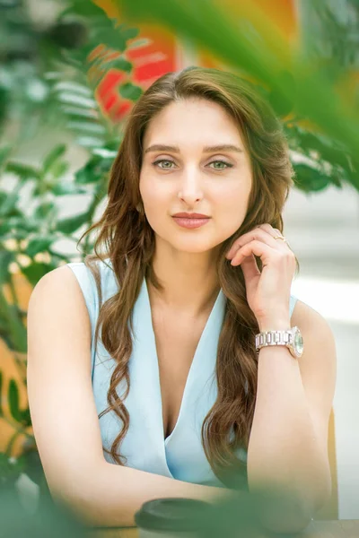 Dışarıdaki çiçek bahçesinde oturan güzel beyaz bir kadının portresi.