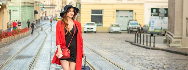 美しい若い白人女性は ヨーロッパの都市でウェット路面電車のトラック上のスーツケースで歩く — ストック写真
