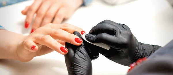 黒手袋のマニキュアマスターの閉鎖は 美容室で紙ナプキンで女性の赤い爪を拭く — ストック写真