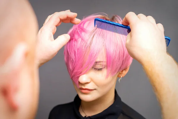 专业的理发师用一个年轻美丽的高加索女人的梳子来检查发型 — 图库照片