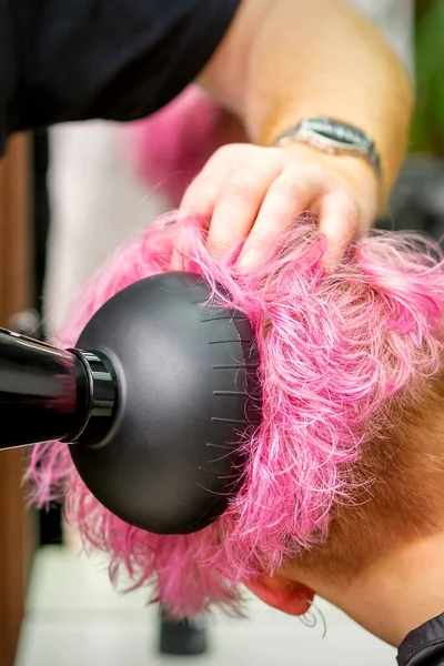 美容室でブロードライヤーで女性のクライアントのスタイリッシュなピンクの髪を乾燥男性の美容師の専門家 — ストック写真