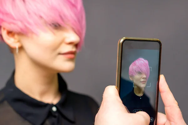 男式理发师的手在智能手机上拍下了她的客户的短粉色发型 — 图库照片