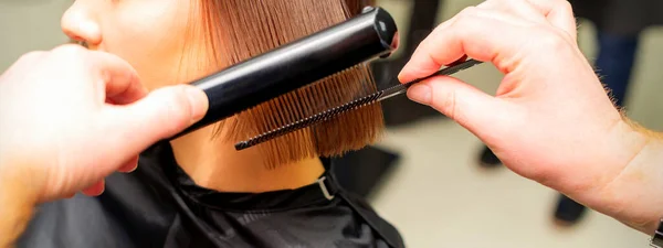 Stylista Włosów Prostuje Krótkie Włosy Młodej Brunetki Płaskim Żelazem Grzebieniem — Zdjęcie stockowe