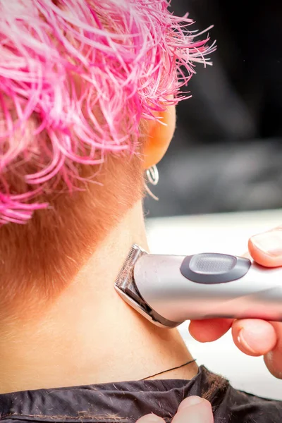在美容院用电剪剪短粉色头发的年轻高加索女人的手 颈的反视 — 图库照片