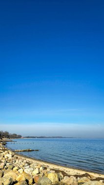 Minimum deniz manzarası, kayalık plaj ve mavi ufuk.