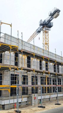 İnşaat halindeki iskeleli bir binanın üstündeki vinç kulesi. Gökyüzünde kopya alanı olan gayrimenkul geliştirme, mimari ve inşaat mühendisliği kavramı.