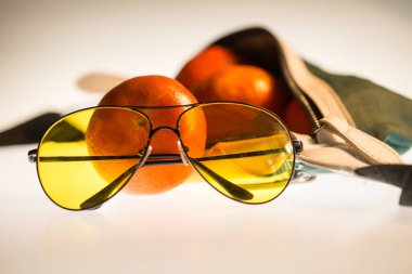 Portakal, güneş gözlüğü ve bir çanta.