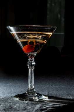 Siyah arka planda kirazlı bir martini bardağı.