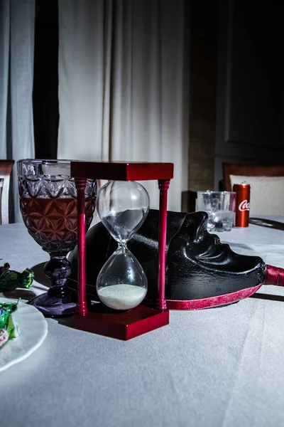 Sand clock with glass of wine and mafia mask