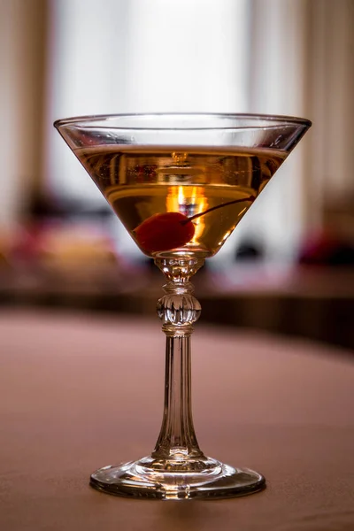 A martini glass with cherry on dark background
