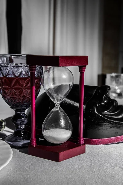 Sand clock with glass of wine and mafia mask