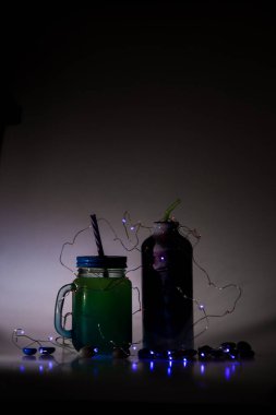 Şişeli ve ampullü yeşil ve mavi kompozisyon. Şişedeki metin kendin ol.