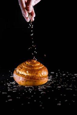 Tohumları siyah arkaplandan dökülen bir ekmek rulosu.