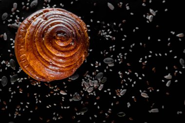 Siyah arka planda tohumları olan bir ekmek rulosu. Üst Manzara. Düz Yatay