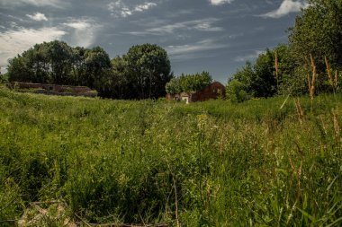 Çimen tarlası ve eski binaları olan kırsal bölge.