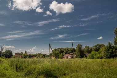 Çimen tarlası ve eski binaları olan kırsal bölge.