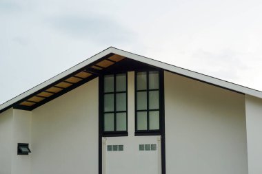 Parlak gökyüzüne karşı uzun siyah çerçeveli pencereleri olan beyaz bir evin ayırt edici modern geçidi..                               