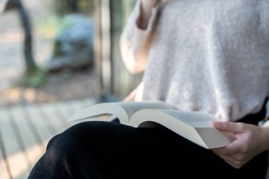 Ormanda bir kulübede kitap okuyan bir kadın.