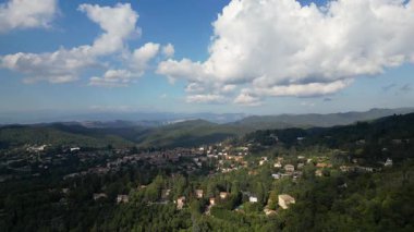 Hava görüntüleri küçük bir kasabayı gösteriyor. Yeşil, ağaçlık bir vadide, dramatik bulut gölgeleri olan.